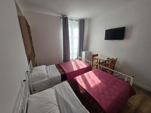 a bedroom with two beds and a television in it at Hôtel de l'Europe in Pantin