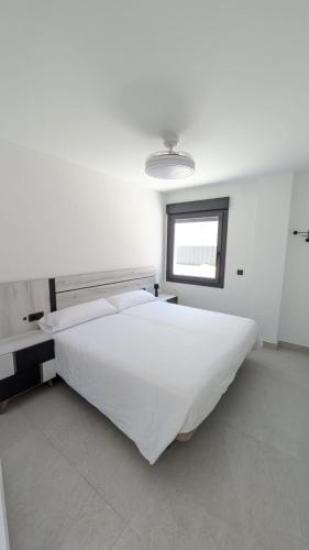 a white bedroom with a large bed and a window at El Callejón in Jaraguas