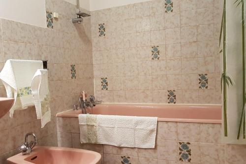 La salle de bains est pourvue d'une baignoire rose et d'un lavabo. dans l'établissement Résidence du Pré Brécel, à Saint-Malo