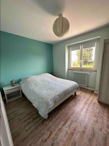 une chambre avec un lit et un mur bleu dans l'établissement Chez Angèle - calme - proche plages - wifi, à Saint-Coulomb