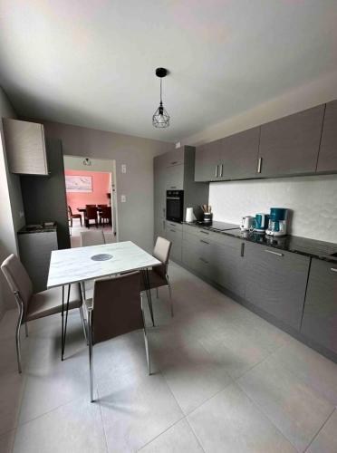 une cuisine avec une table et des chaises dans une pièce dans l'établissement Chez Angèle - calme - proche plages - wifi, à Saint-Coulomb