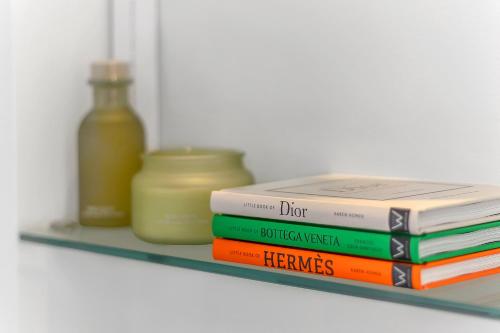 une pile de livres posée sur une étagère avec une bouteille dans l'établissement Croisette 65 apartment-Miramar residence, à Cannes