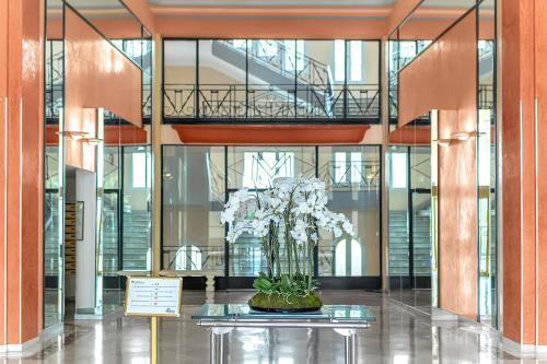 un vase de fleurs blanches sur une table dans un bâtiment dans l'établissement Croisette 65 apartment-Miramar residence, à Cannes