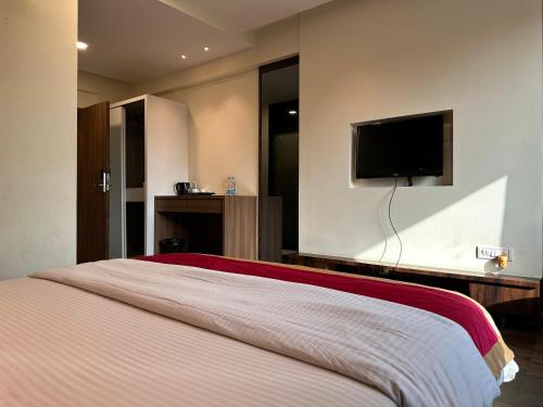 a bedroom with a bed with a tv on the wall at Farm Regency in Mumbai