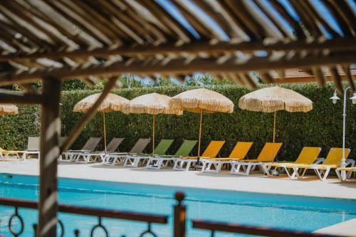 a group of chairs and umbrellas next to a swimming pool at Casa Marana by Le Lido in Lucciana