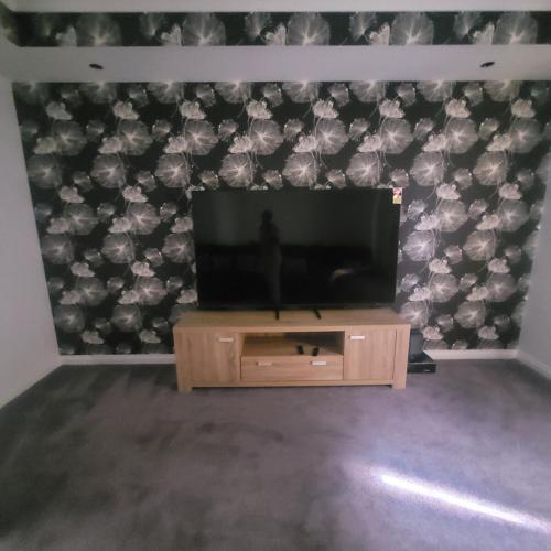 a flat screen tv sitting on top of a wooden entertainment center at Home away from home in Yanchep