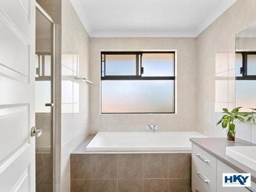 a white bathroom with a tub and a window at Home away from home in Yanchep
