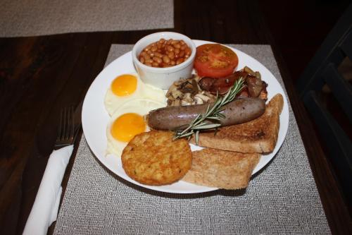 a plate of breakfast food with eggs sausage bread and beans at Avoca Vale Country Hotel in Louis Trichardt