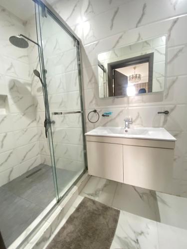 a white bathroom with a sink and a shower at Executive One bed - East legon in Accra
