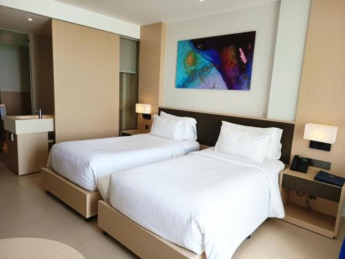 two beds in a hotel room with white sheets at Sarang Arena Cam Ranh Seaview Resort condotel in Cam Ranh International Airport
