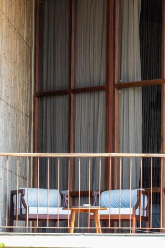 a balcony with two chairs in front of a window at Sanctuary Chitwan National Park in Chitwan