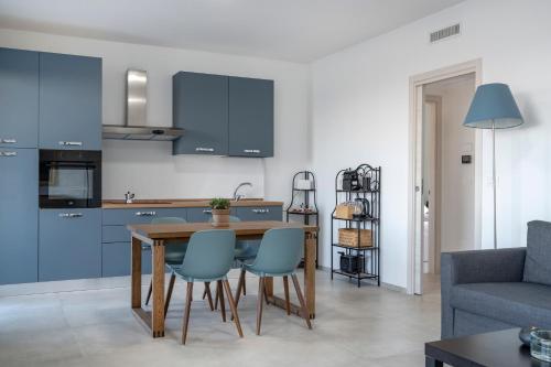 a kitchen with blue cabinets and a table and chairs at Pausa Mare Outside in Torre a Mare