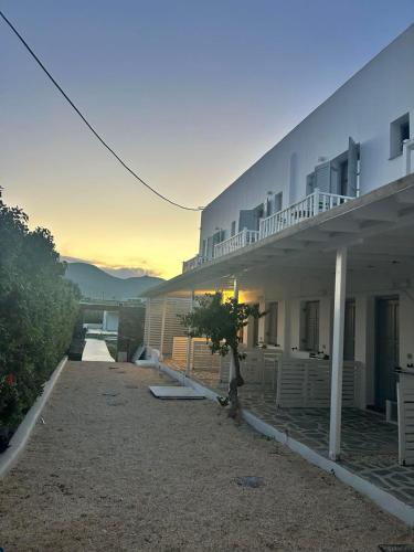 a large white building with a sunset in the background at Fisilanis Beachfront Hotel in Logaras