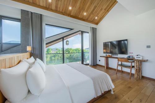 a bedroom with a large bed and a large window at Anji Pu An Tea House Hotel in Anji