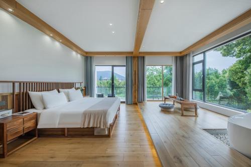 a bedroom with a bed and a tub and windows at Anji Pu An Tea House Hotel in Anji