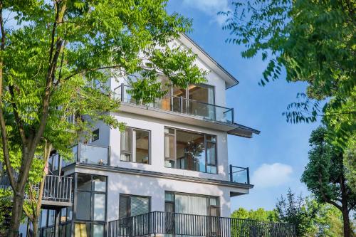 a white house with a balcony and trees at Anji Pu An Tea House Hotel in Anji