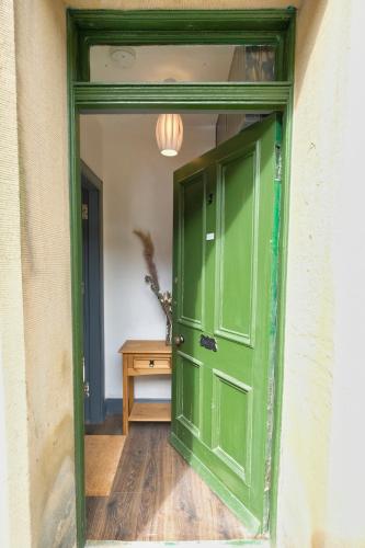 an open green door in a room with a table at Cosy Ground Floor Victorian Flat in the Heart of Hawick in Hawick