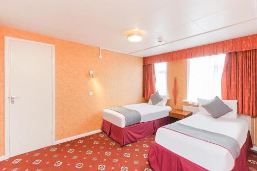 a hotel room with two beds and a window at OYO Stade Court Hotel in Hythe
