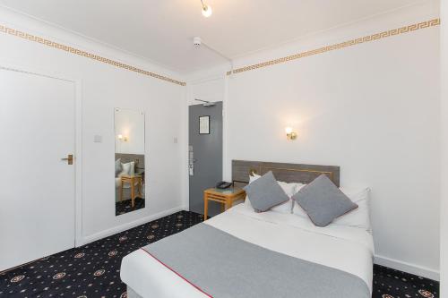 a bedroom with a white bed with blue pillows at OYO Stade Court Hotel in Hythe
