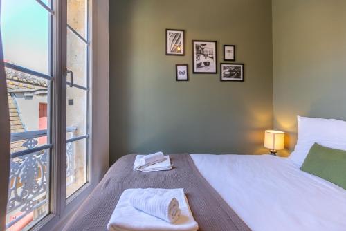 a bedroom with a bed and a large window at Le Figuier - Confortable T2 en centre historique in Bergerac
