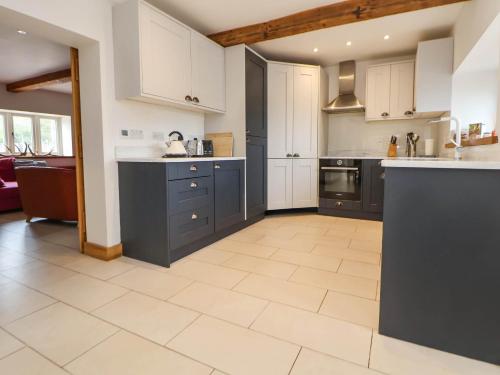 a large kitchen with white cabinets and blue appliances at Sprinks Farm in Leek