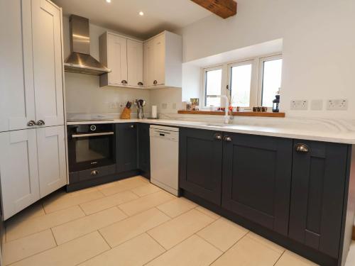 a kitchen with black and white cabinets and a sink at Sprinks Farm in Leek