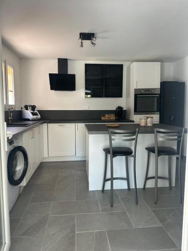 une cuisine avec des armoires blanches et des comptoirs noirs dans l'établissement Appartement maison copropriété, à Tourbes