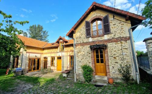 une vieille maison en pierre avec des portes et des fenêtres jaunes dans l'établissement Charmante Maison avec Parc entre Seine et Forêt de Fontainebleau à 30mn de Paris, à Bois-le-Roi