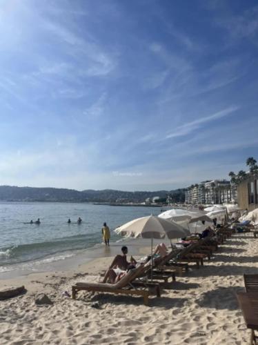 un groupe de personnes assises sur une plage avec des parasols dans l'établissement Apartment sea side, à Antibes