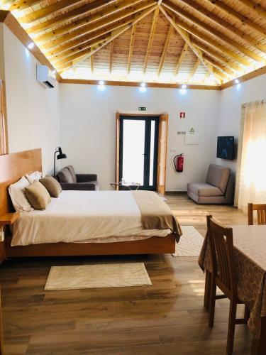 a bedroom with a large bed and a living room at AMU- Apartamentos Mistérios da Urzelina in Urzelina