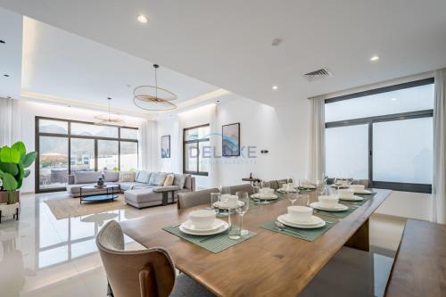 a dining room and living room with a table and chairs at Blue Marble Beach 4BR Villa with Assistants Room, Private Pool, Access to Floating Pier, and Sea and Mountain Views, Al Dana Island, Fujairah by Deluxe Holiday Homes in Fujairah