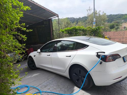 a white car is being charged by a blue hose at Oleum in Massa Lubrense