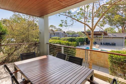 a deck with a wooden table and chairs on a balcony at Peppers Hunter Valley AVC Apartment in Rothbury