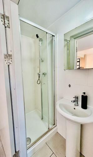 a white bathroom with a shower and a sink at Heart of Dalston East London in London