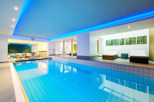 a large swimming pool in a house with blue lighting at Hotel Ambassador in Bern