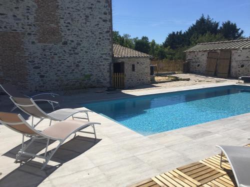 un patio avec deux chaises et une piscine dans l'établissement LA GRANDE THIBAUDIERE, à La Plaine