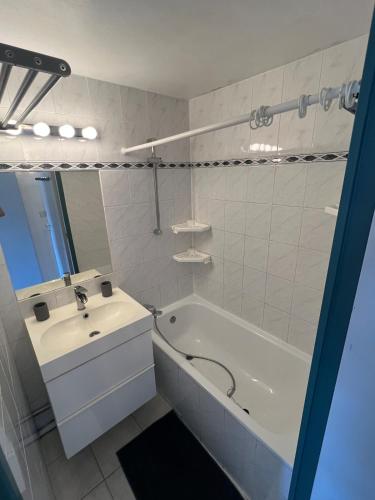 La salle de bains blanche est pourvue d'un lavabo et d'une baignoire. dans l'établissement Appartement climatisé, double vue mer et Pic, accès mer et Parking privatif, à Palavas-les-Flots