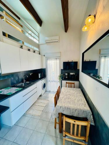 une cuisine avec une table et des chaises et une cuisine avec des armoires blanches dans l'établissement Appartement climatisé, double vue mer et Pic, accès mer et Parking privatif, à Palavas-les-Flots