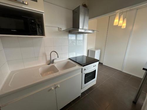 une cuisine blanche avec un évier et un micro-ondes dans l'établissement Mykonos, 4 Pers, Lumineux, Familial, Spacieux, à La Celle-sous-Gouzon