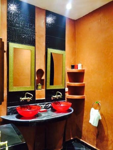a bathroom with two red sinks and two mirrors at Etablissement moderne in Safi