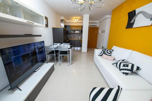 Una sala de estar con un sofá blanco y un televisor. en La Rosa, en Gran Tarajal