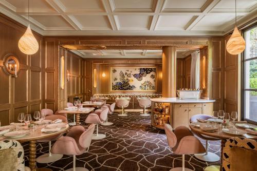 a restaurant with tables and chairs in a room at Le Pavillon de la Reine & Spa, Place des Vosges in Paris