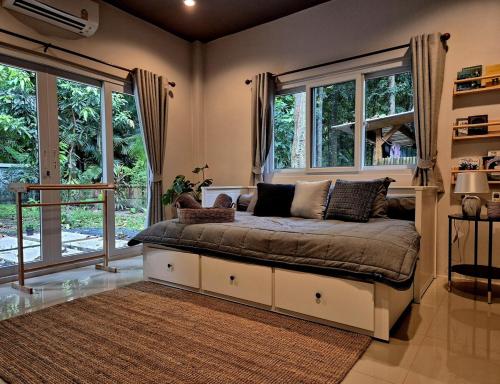 a bedroom with a large bed with windows at Villa Tsukino Usagi in Koh Phangan