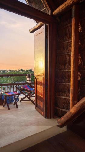 an open door of a log cabin with a deck with a table at Exe El Pueblito in Holbox Island