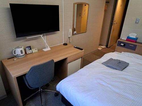 a hotel room with a desk with a television and a bed at Hotel Tetora Spirit Sapporo in Sapporo