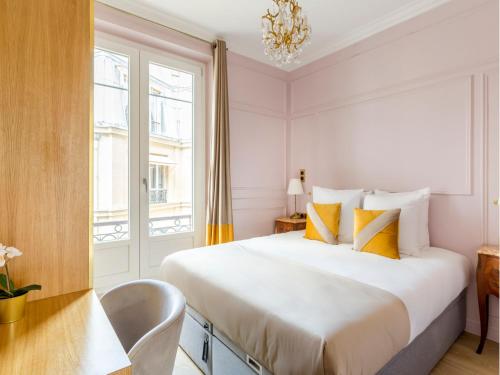 - une chambre avec un grand lit blanc et des oreillers jaunes dans l'établissement Merveil - Luxury Suite - Louvre - Opera I, à Paris