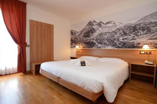 a hotel room with a bed and a painting on the wall at Park Residence Imperator in Carisolo