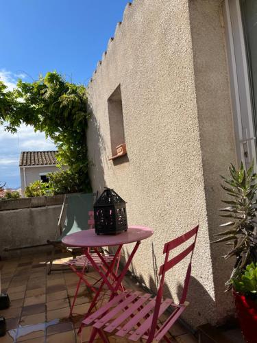 une table rose et deux chaises sur la terrasse dans l'établissement Cocon, à Saint-Nazaire