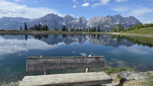 a bench sitting in front of a lake with mountains at Urlaub in der Bergdoktor-Region Wilder Kaiser Terrasse Bergdoktor-Drehorte in der Nähe ITD098 in Itter