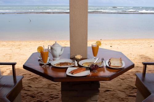 a table with food and drinks on the beach at Hotel Coconut Bar Sea Lodge in Beruwala
